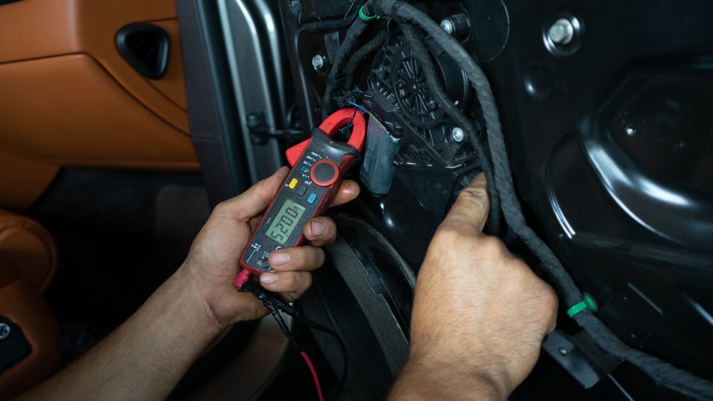 Hands Using a Digital Multimeter to Test Wiring Inside a Car Door Panel — AA Automotive Repairs in Forster, NSW