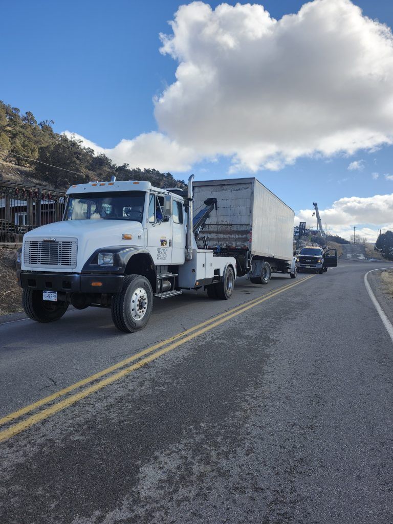 White semi-truck with trailer parked on a rural road under a partly cloudy sky