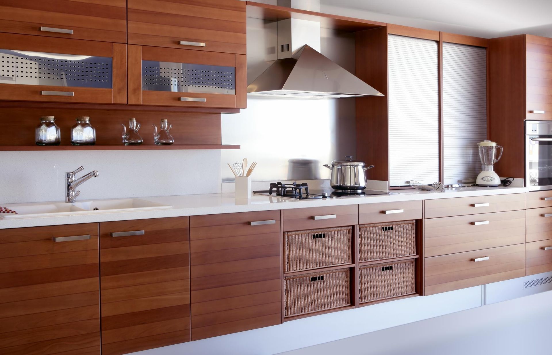 Modern wooden kitchen with white countertop, stainless range hood, and wicker cabinet doors