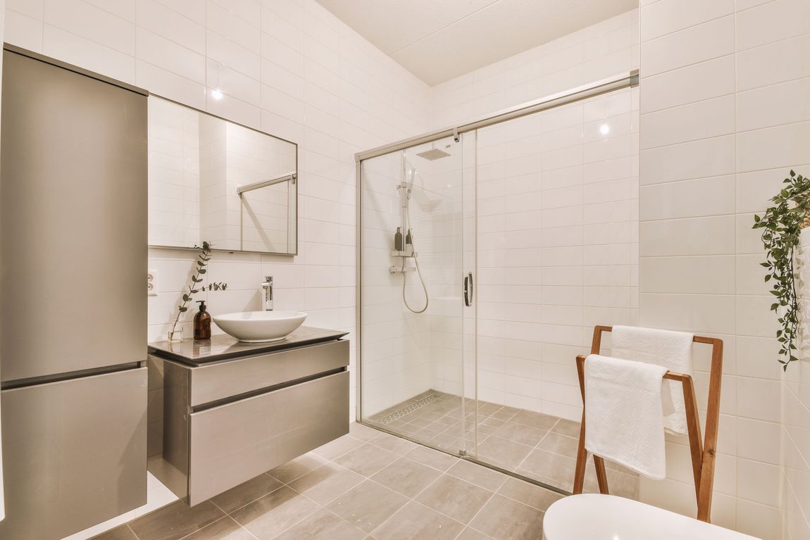 Modern white bathroom with vanity, mirror, glass shower, and towel rack