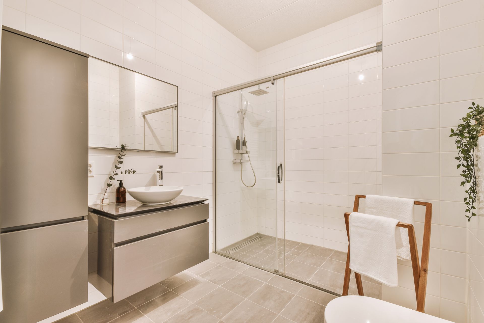 Modern bathroom with a glass shower, vanity, mirror, and white tile walls