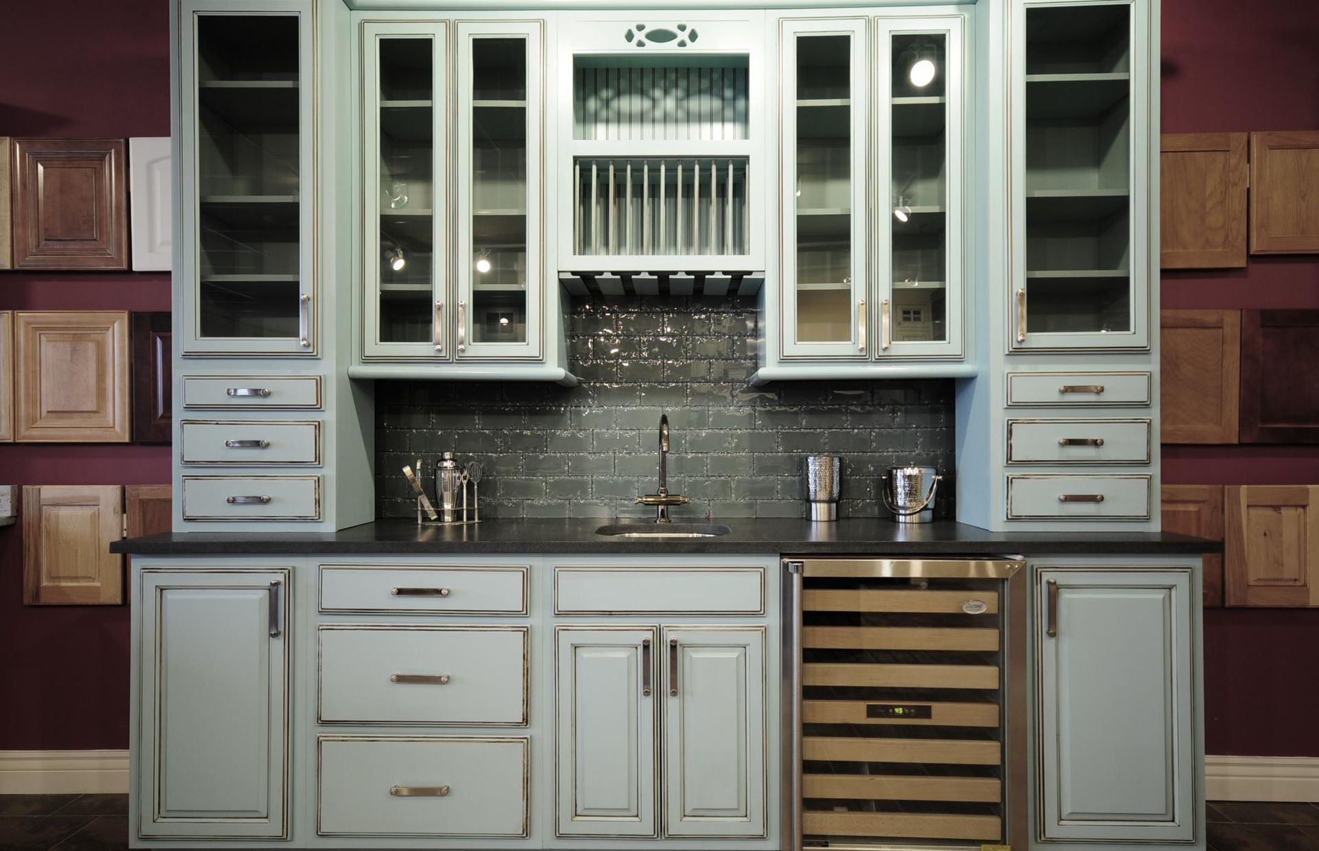 Built-in kitchen cabinetry with white glass-front cabinets, gray counters, and a dark tile backsplash