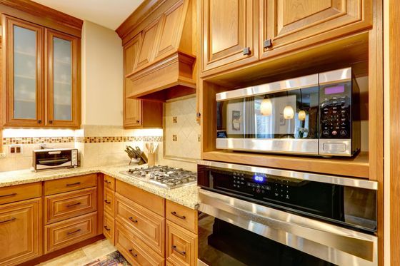 Wooden kitchen with cabinets, granite counters, and built-in stainless microwave and oven.