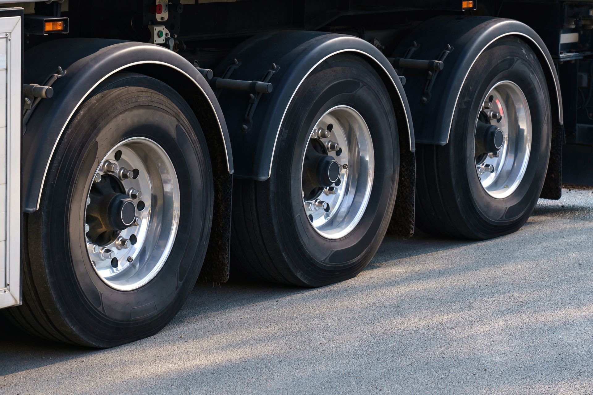 Close-up of three black truck wheels and tires on a vehicle parked on pavement.