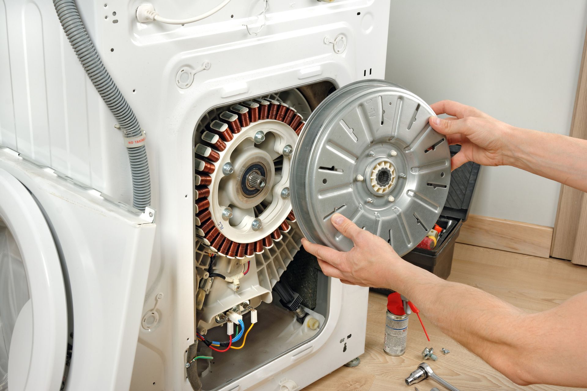 A person is taking the motor out of a washing machine.