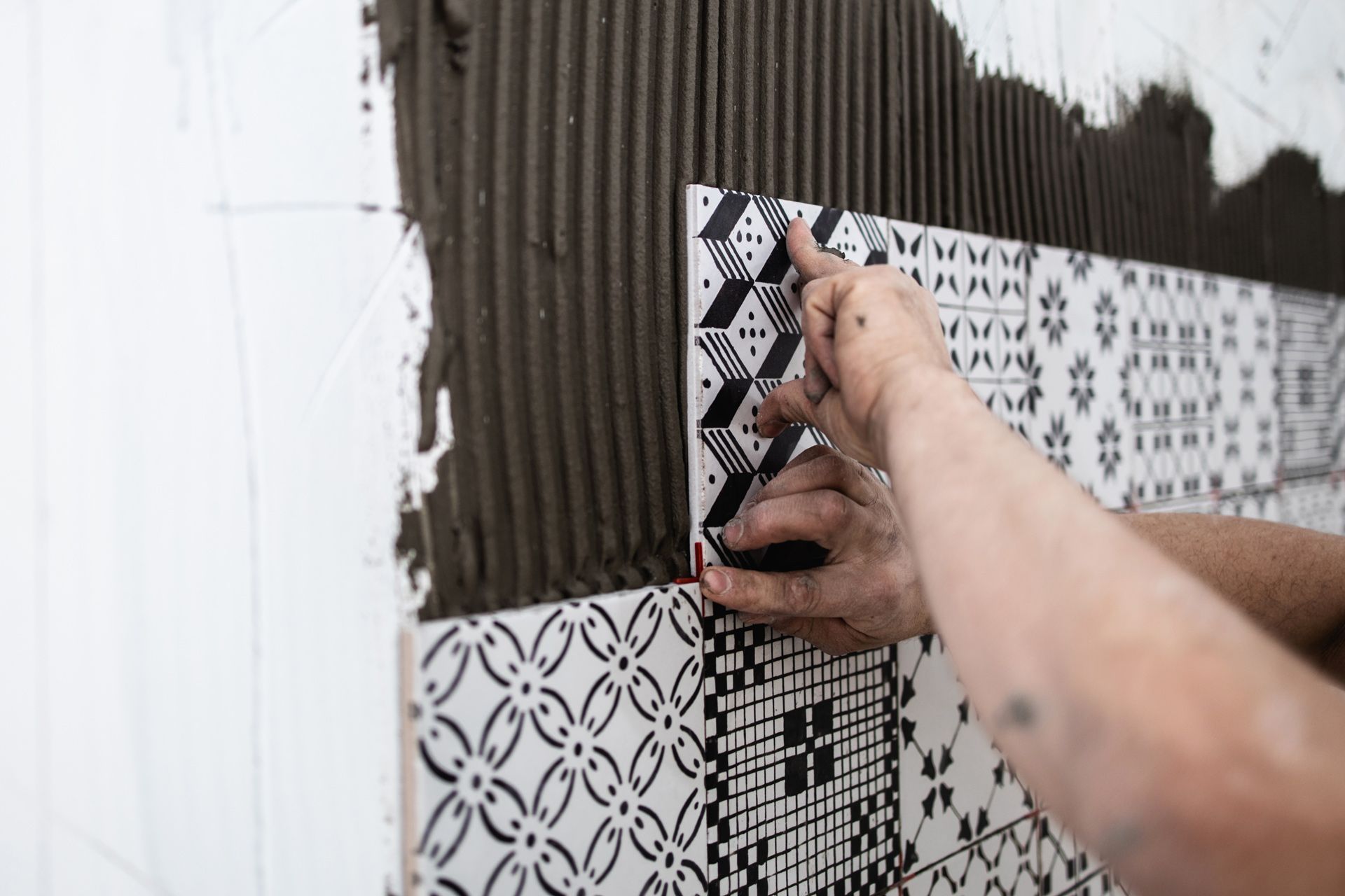 A person is laying tiles on a wall.