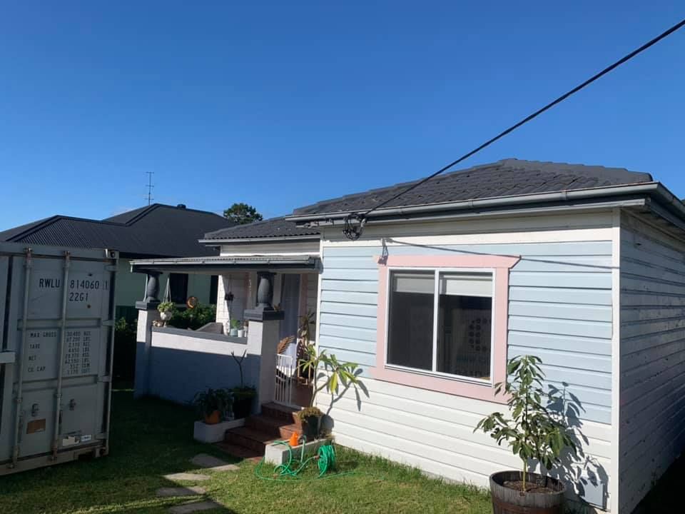 A Small House With a Pink Window and a Shipping Container in Front of It — Craig Allman Construction Pty Ltd In Fernhill, NSW