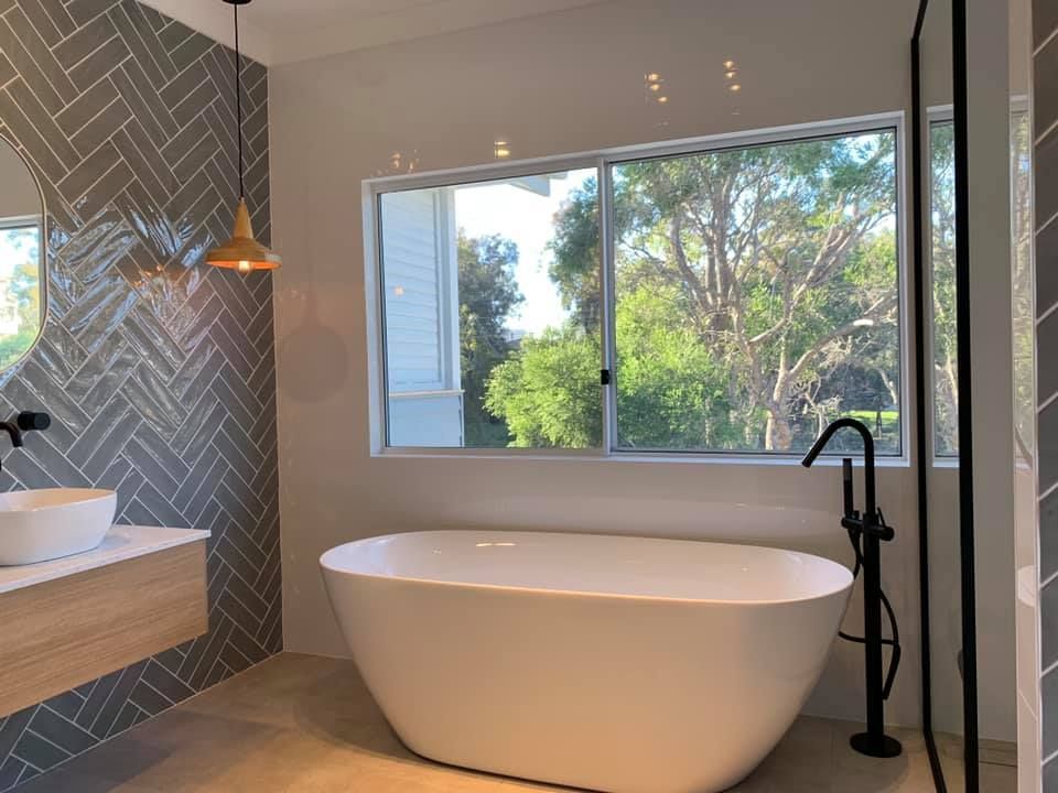 A Bathroom With a Bathtub, Sink, Mirror and Window — Craig Allman Construction Pty Ltd In Fernhill, NSW