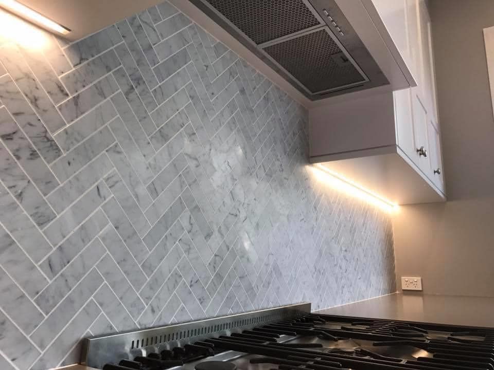 A Kitchen With a Stove Top Oven and Marble Tiles on the Wall — Craig Allman Construction Pty Ltd In Fernhill, NSW
