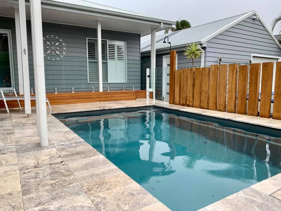 A Large Swimming Pool in Front of a House With a Wooden Fence — Craig Allman Construction Pty Ltd In Fernhill, NSW