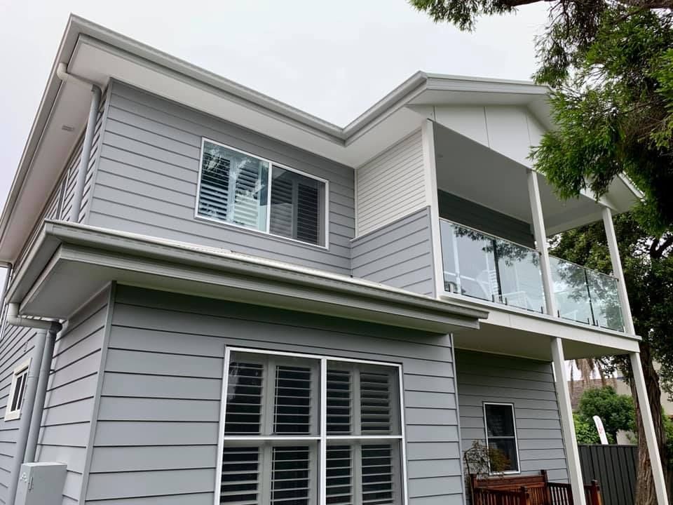 A Large Gray House With a Balcony and Lots of Windows — Craig Allman Construction Pty Ltd In Fernhill, NSW