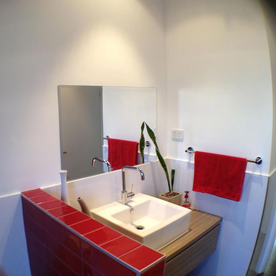 A Bathroom With a Sink a Mirror and Red Towels — Craig Allman Construction Pty Ltd In Shellharbour, NSW