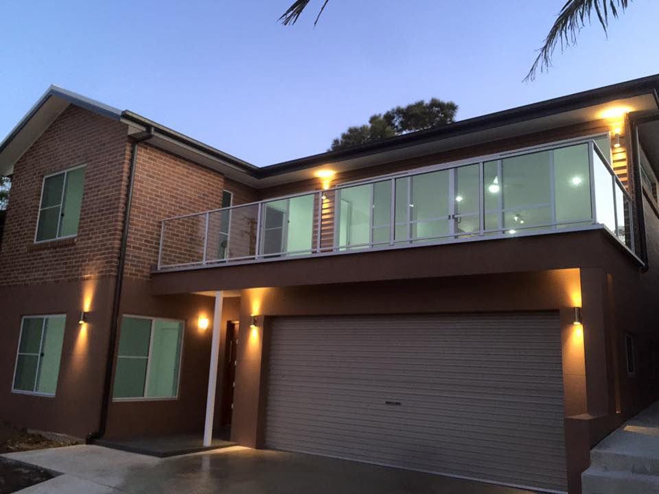 A House With a Balcony and a Garage is Lit Up at Night — Craig Allman Construction Pty Ltd In Fernhill, NSW