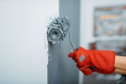 A person is painting a wall with a paint roller.