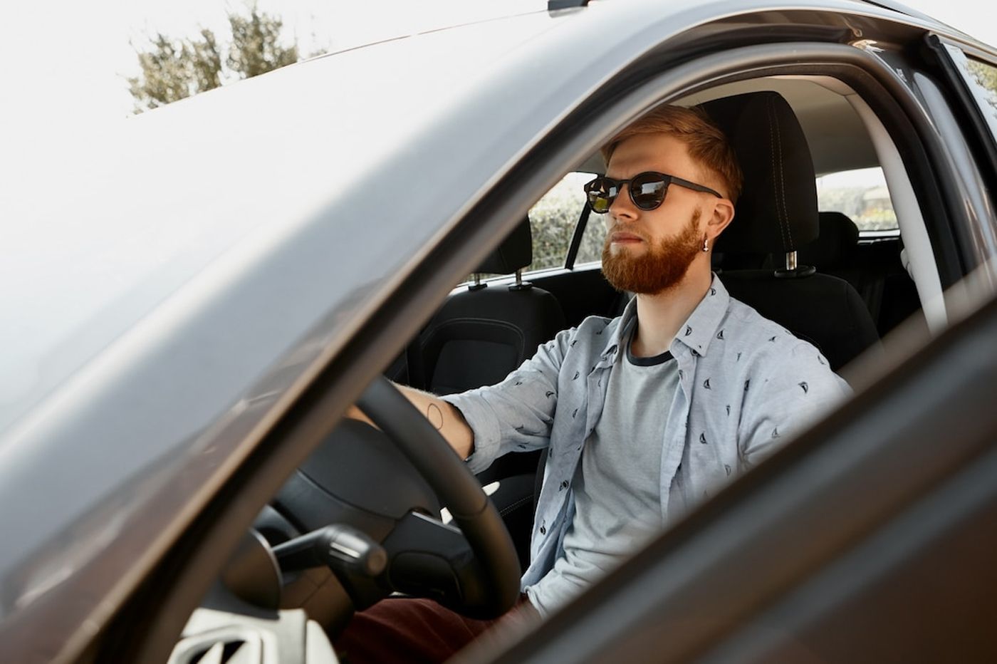A bearded man wearing sunglasses driving a car in Houston.