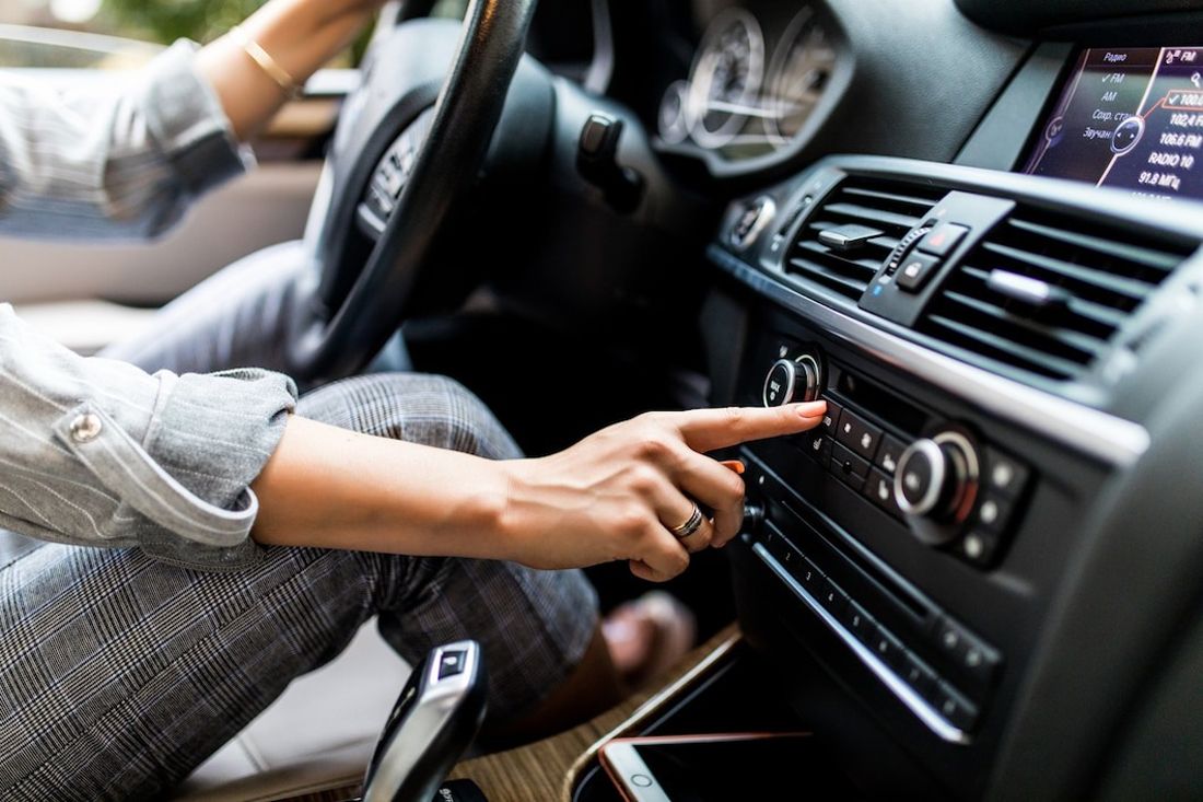 A person adjusting the car's audio system while sitting in the driver's seat.
