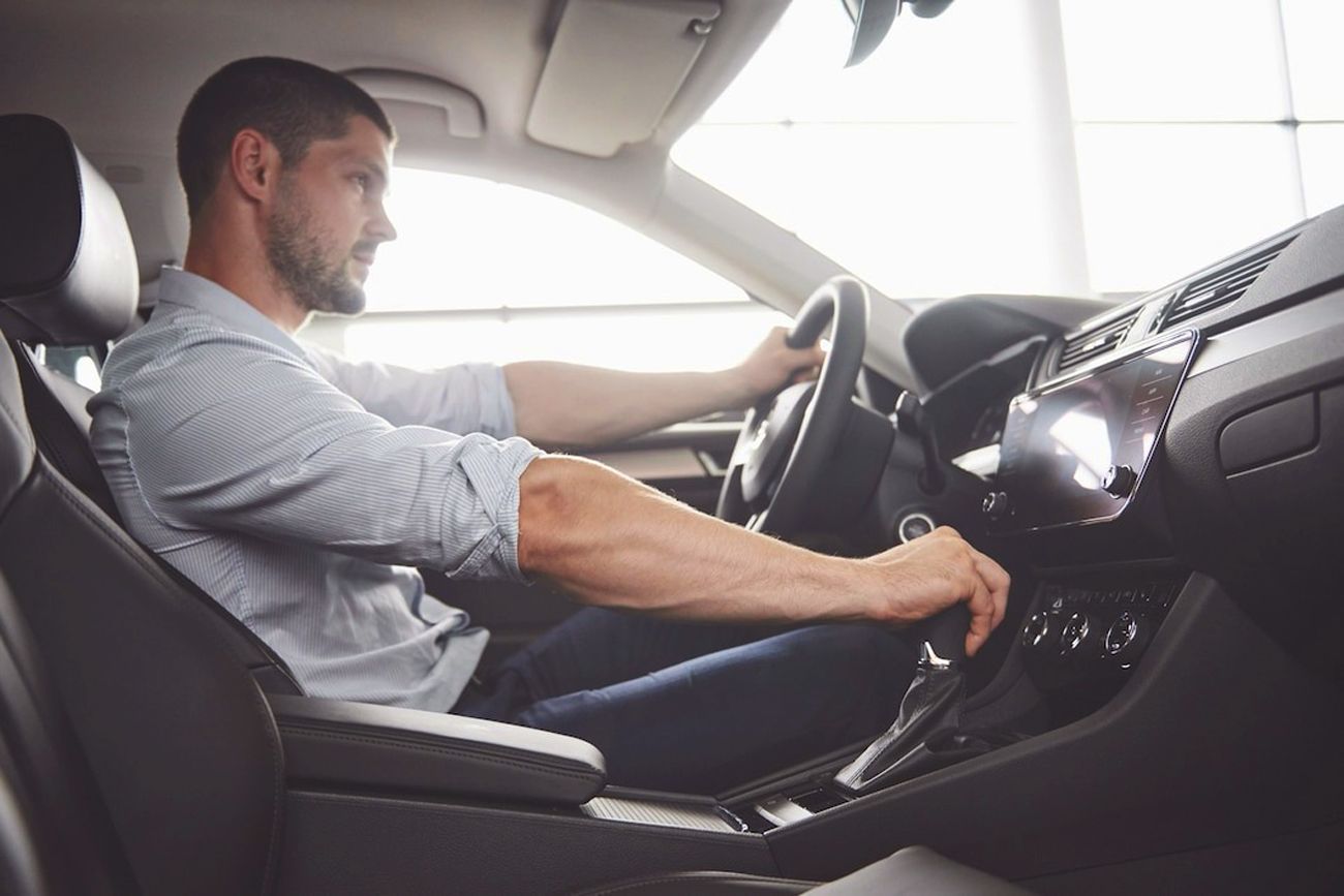 Man operating the gear shift in a vehicle while driving.