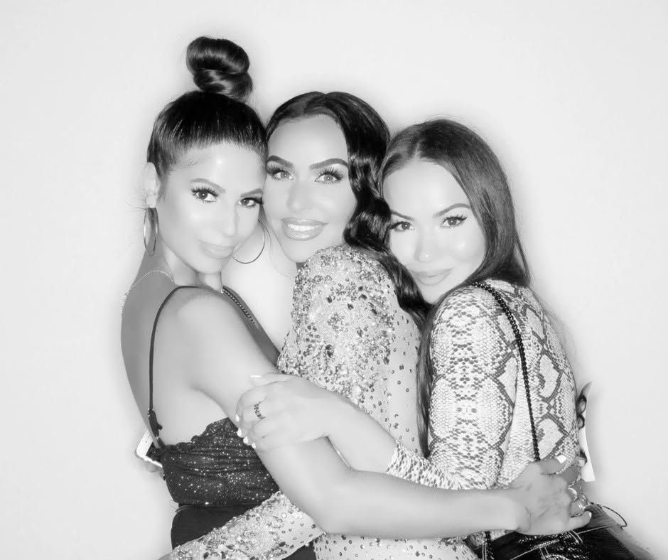 Three people posing closely together and smiling in a black-and-white portrait.