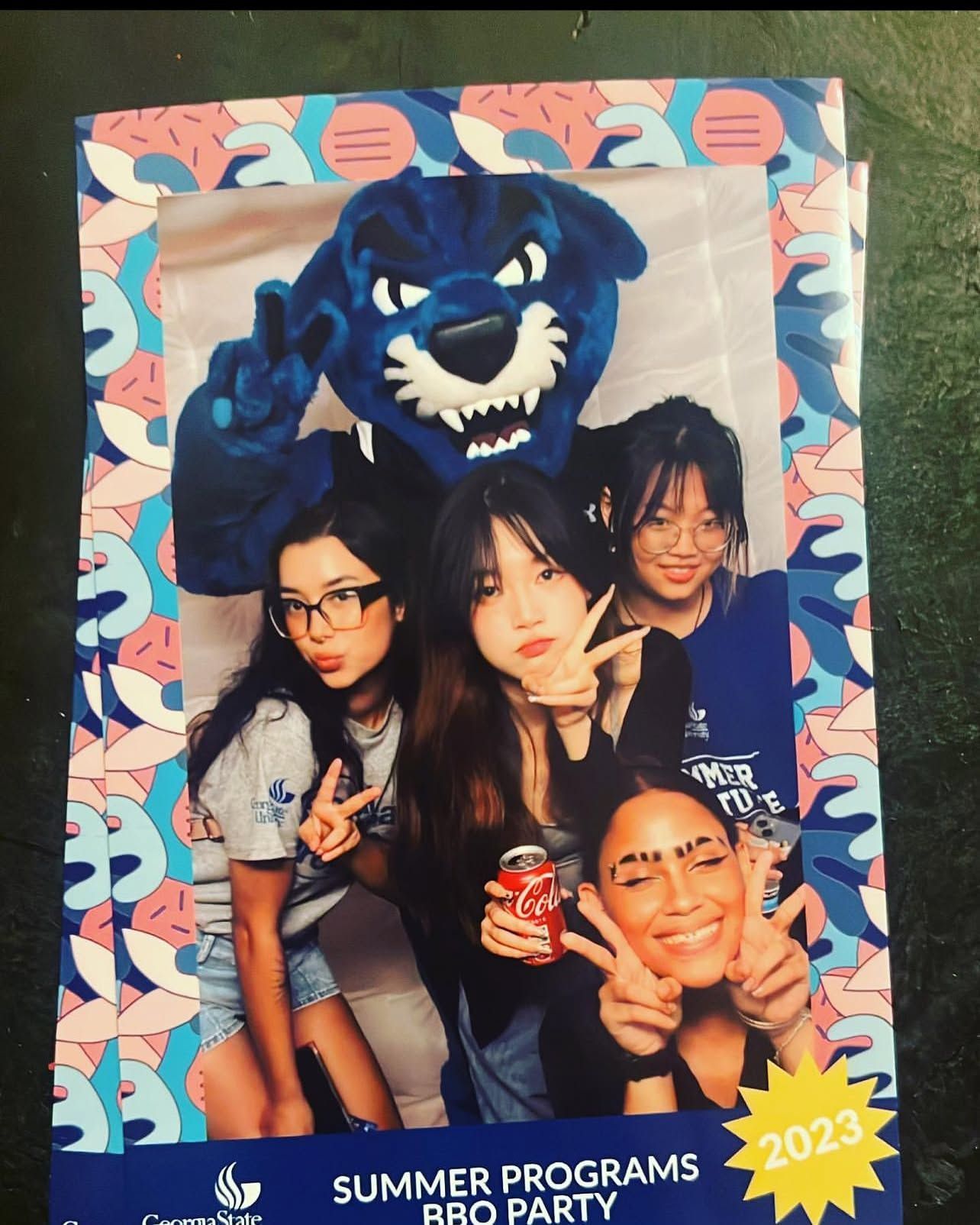 Four people pose with a blue mascot; colorful frame reads “Summer Programs 2023.”