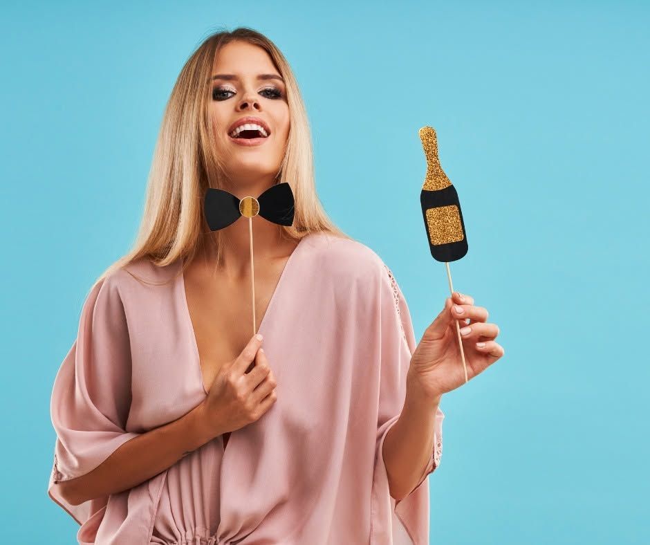 Blonde person in a pink dress holds a black-and-gold microphone against a blue background.