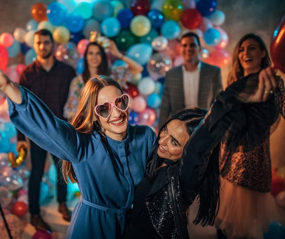People dancing at a colorful party with balloons in the background