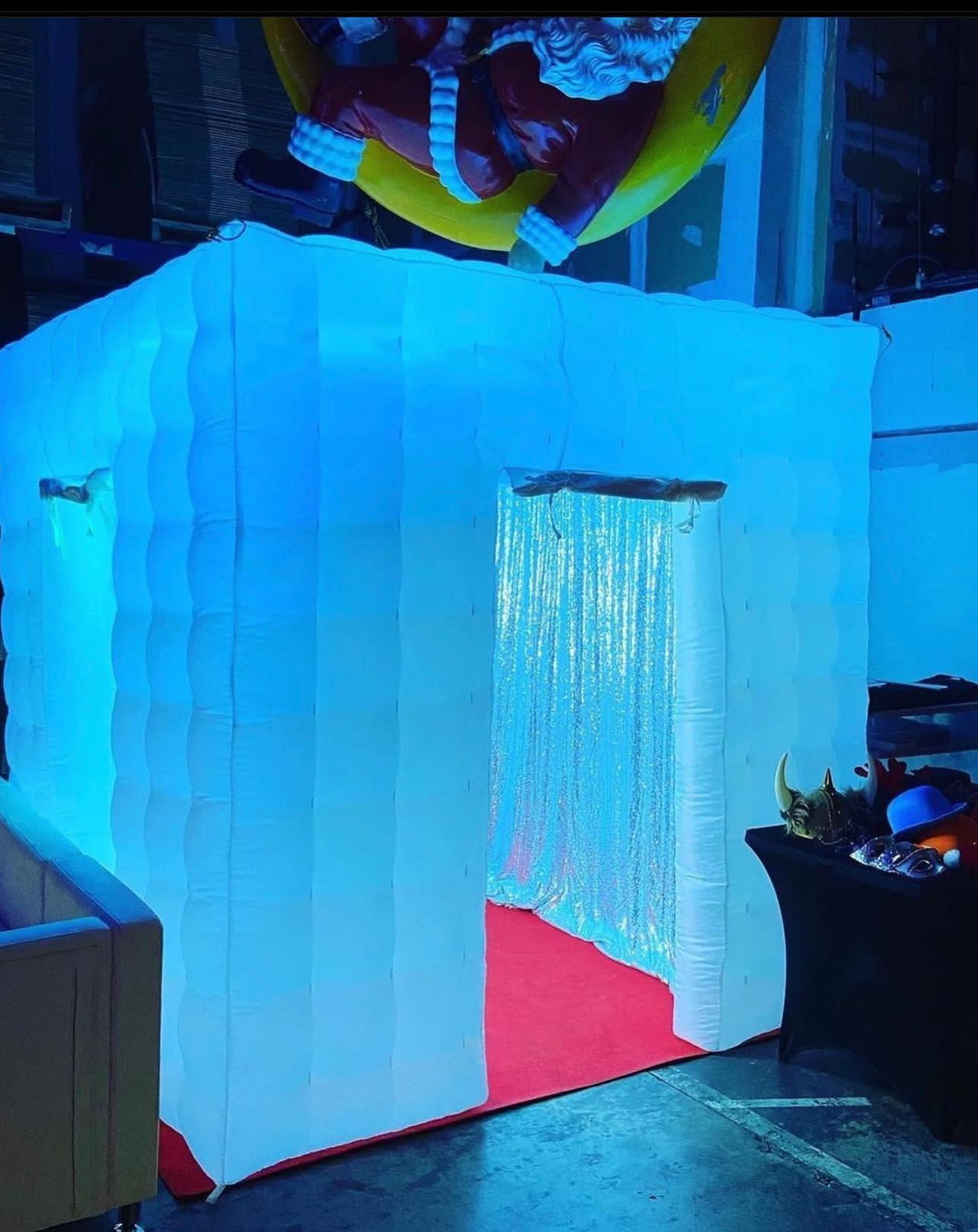 Blue-lit white booth entrance with a red floor and hanging curtain fringe
