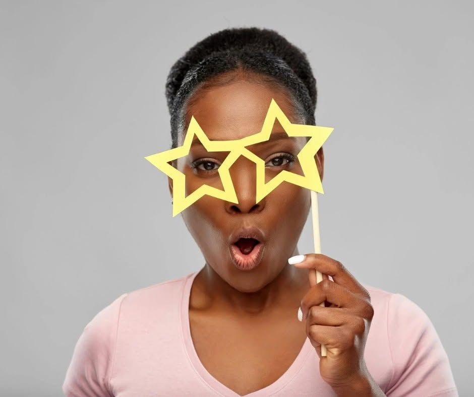 Person blowing bubbles through yellow star-shaped glasses against a gray background