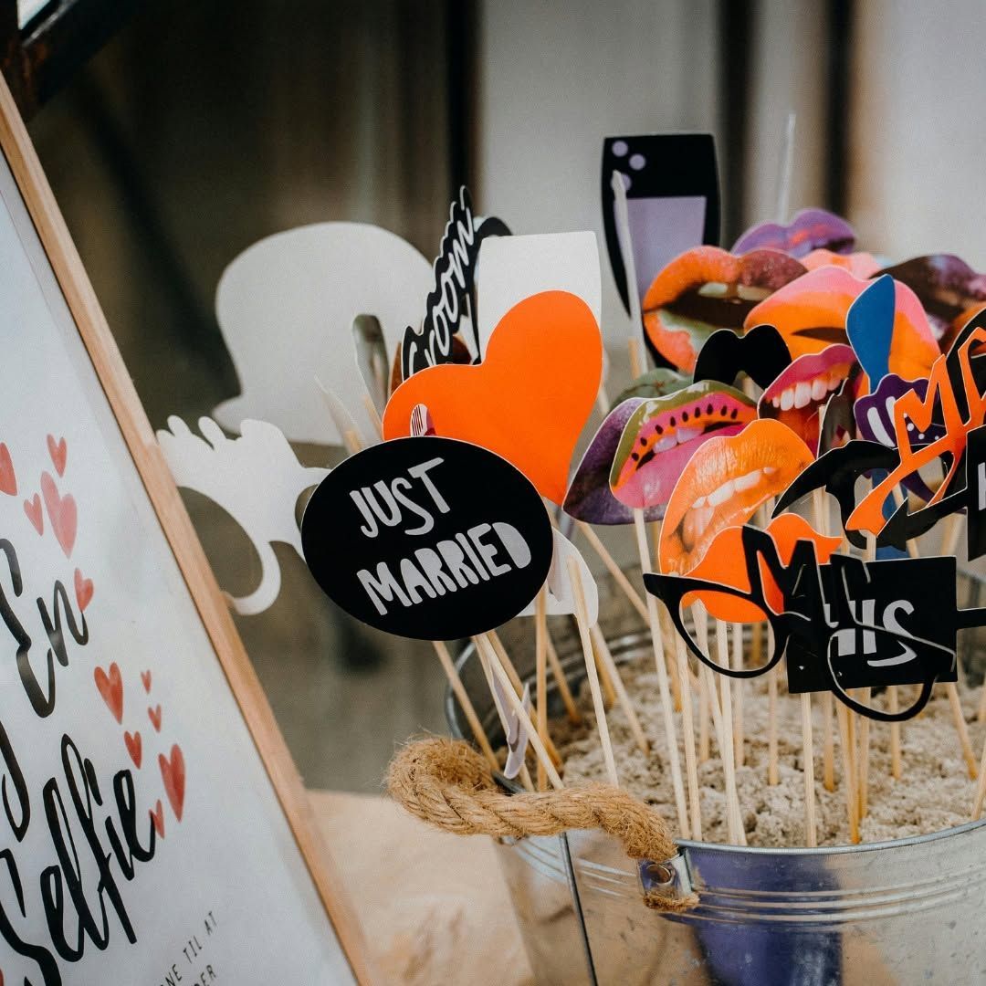 Wedding photo booth props in a bucket, including a “Just Married” sign and colorful glasses.