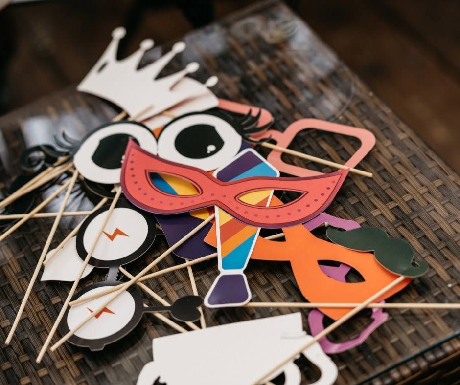Colorful carnival masks and props on a woven tray, including a red-orange eye mask and crown cutouts