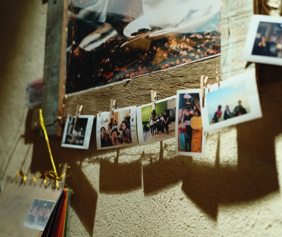 Photos clipped to a string on a textured wall, with sunlight casting long shadows.