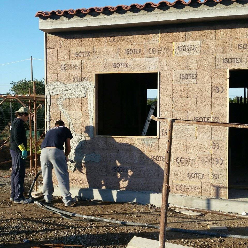 Due persone lavorano sulla facciata di un edificio con blocchi 