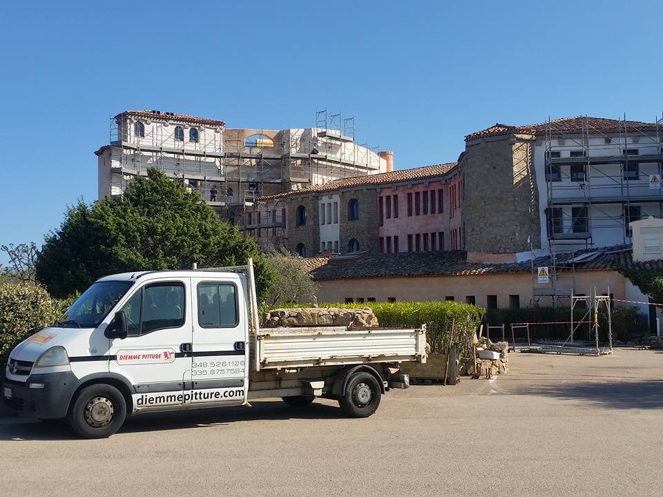 Un camion da lavoro bianco parcheggiato davanti agli edifici, alcuni dei quali in costruzione; il cielo è azzurro.
