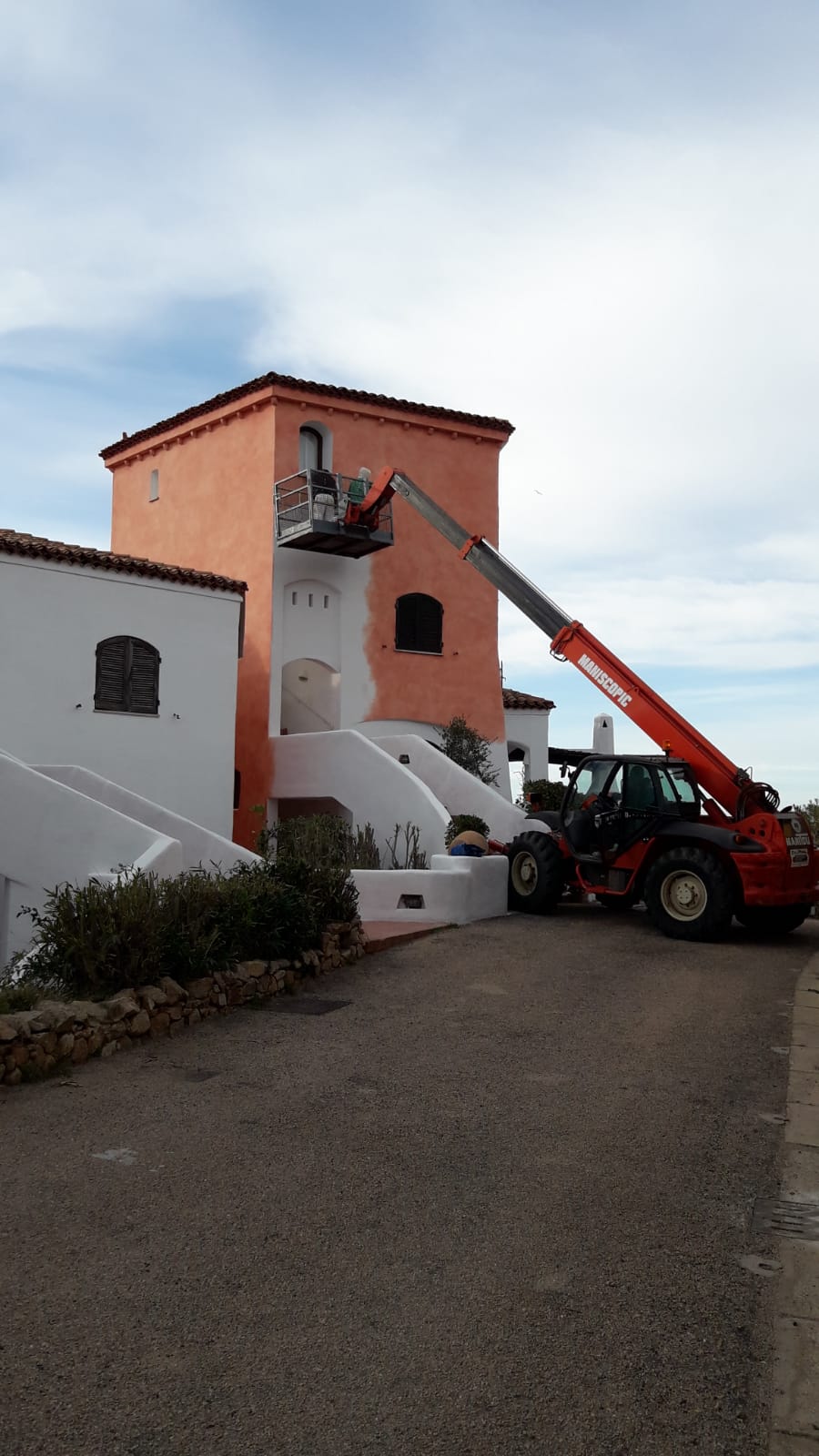 Una persona in ascensore sta dipingendo la torre arancione di un edificio. 