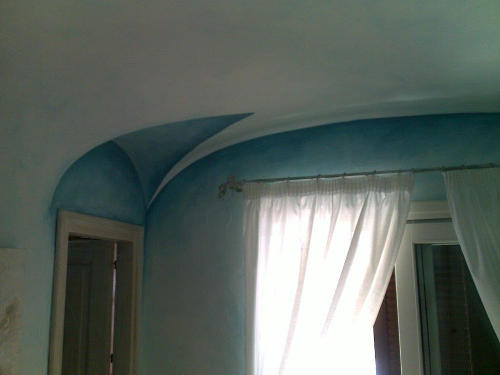 Soffitto ad arco dipinto di blu sopra una finestra con tende bianche e cornice della finestra.