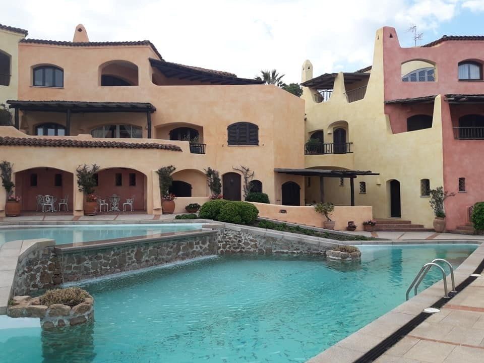 Una piscina di fronte a colorati edifici in stile mediterraneo.