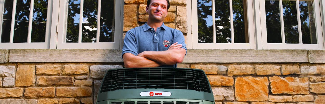 Trane Technician Standing Behind Heat Pump — Jacksonville, FL — Willman Air Trane Technician Standing Behind Heat Pump — Jacksonville, FL — Willman Air