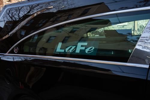 Car door window with turquoise “LaFe” decal on a black vehicle