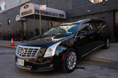 Black Cadillac SUV parked outside a building entrance with orange cones nearby