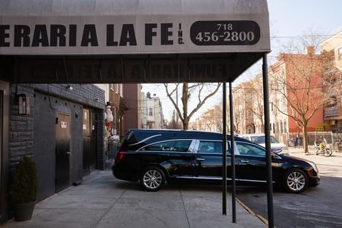 Black hearse parked by a storefront awning with the sign 