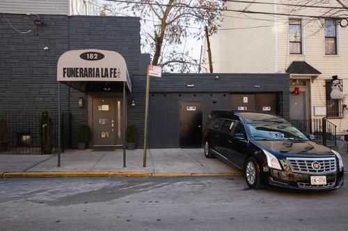 Funeral home storefront with a black sedan parked outside on a city street