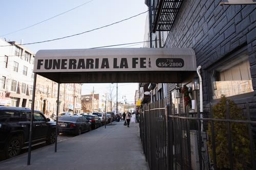 Street view of a storefront awning reading “FUNERARIA LA FE” along a city sidewalk.