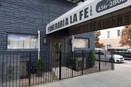 Funeraria La Fe storefront with black gate and arched awning on a city sidewalk