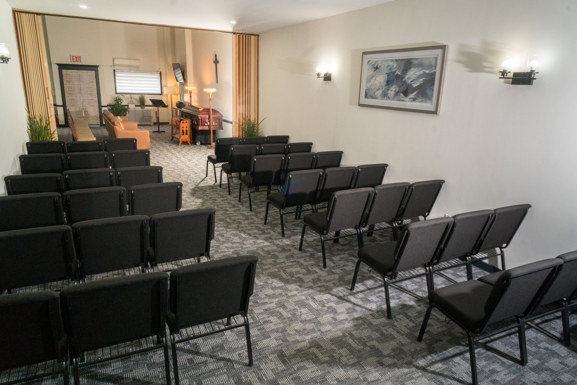 Wood-paneled meeting room with rows of red chairs and tables facing the front
