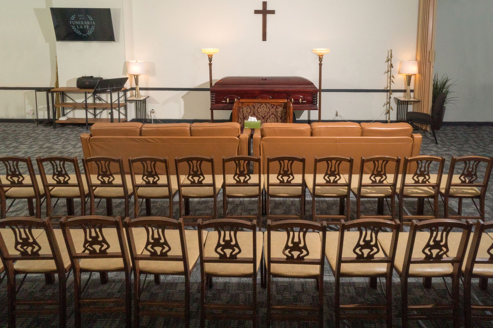 Church sanctuary with rows of wooden pews facing an altar and cross on the wall