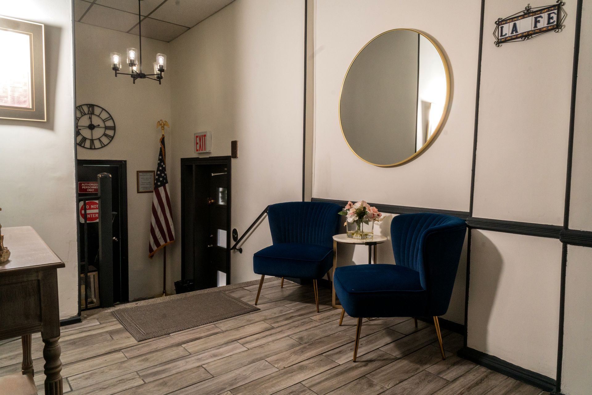 Elegant hallway lobby with American flag, chair, mirror, console table, and floral arrangements