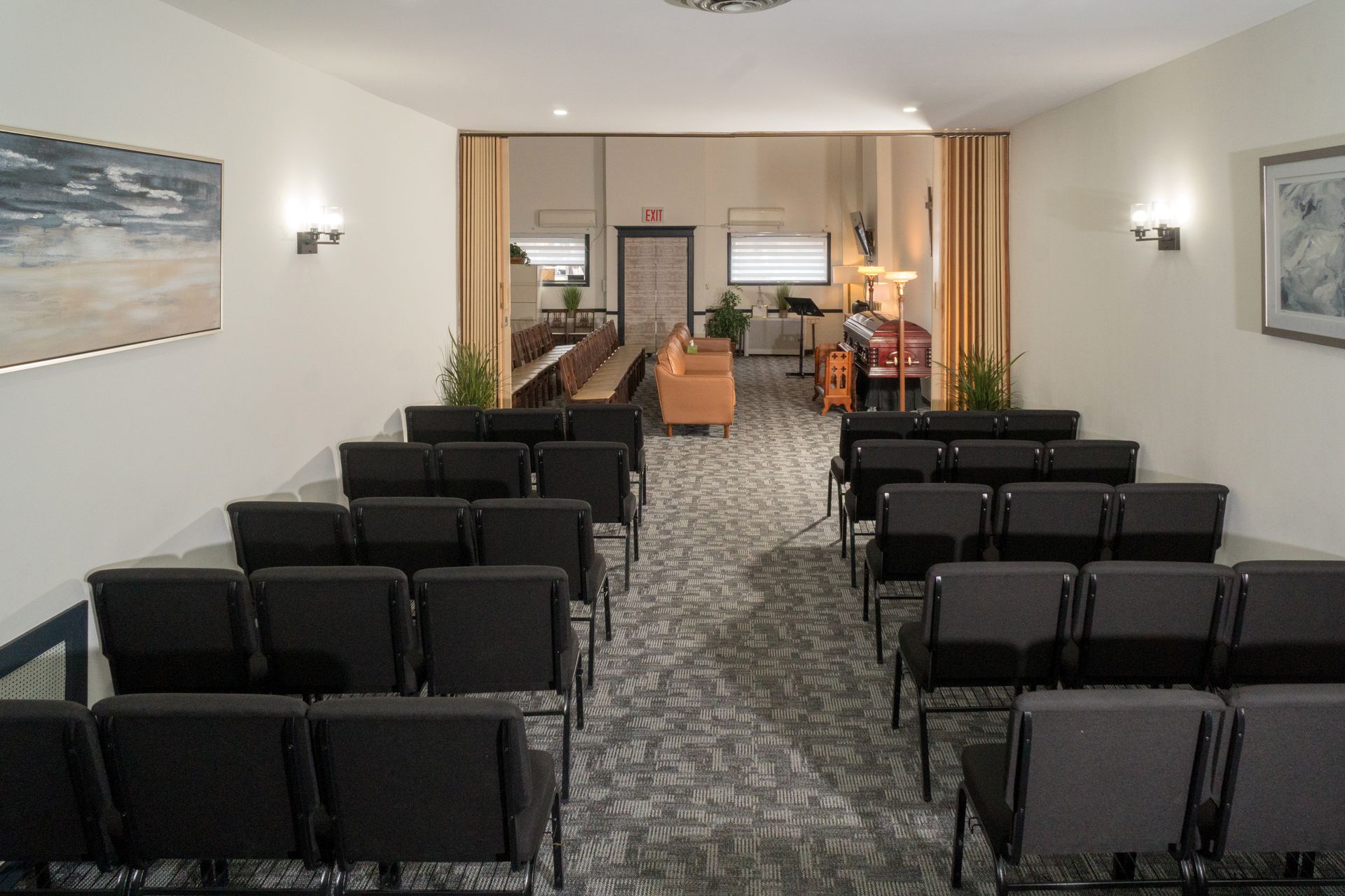 Empty waiting room with rows of red chairs, wood-paneled walls, and a small front desk in the distance