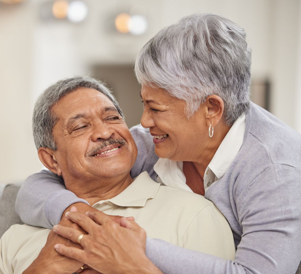 Smiling couple embracing on a sofa in a softly lit living room
