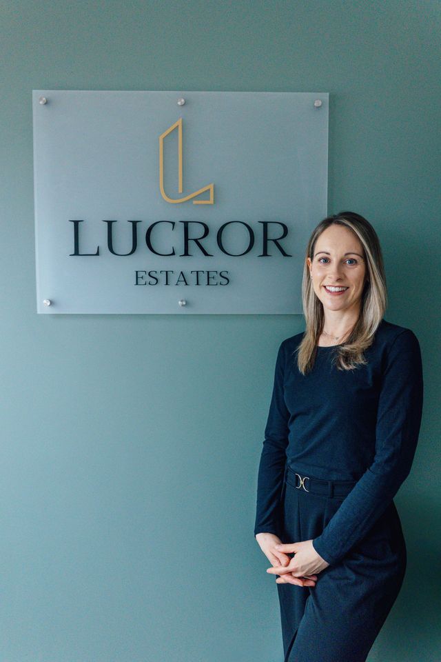 A man is sitting at a table in front of a sign that says lucror estates.