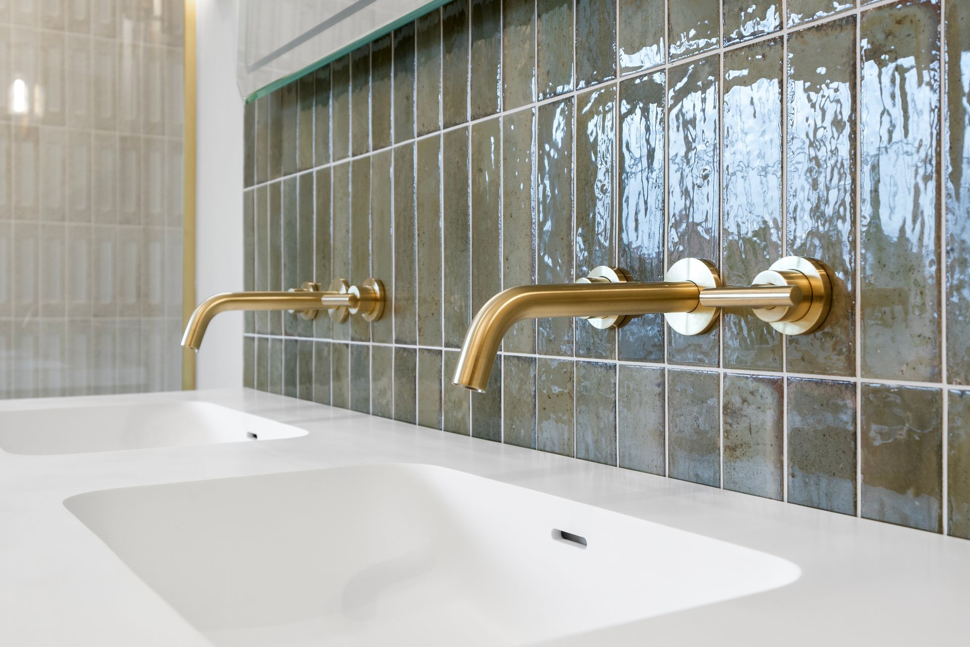 A bathroom with two sinks and brass faucets on the wall.