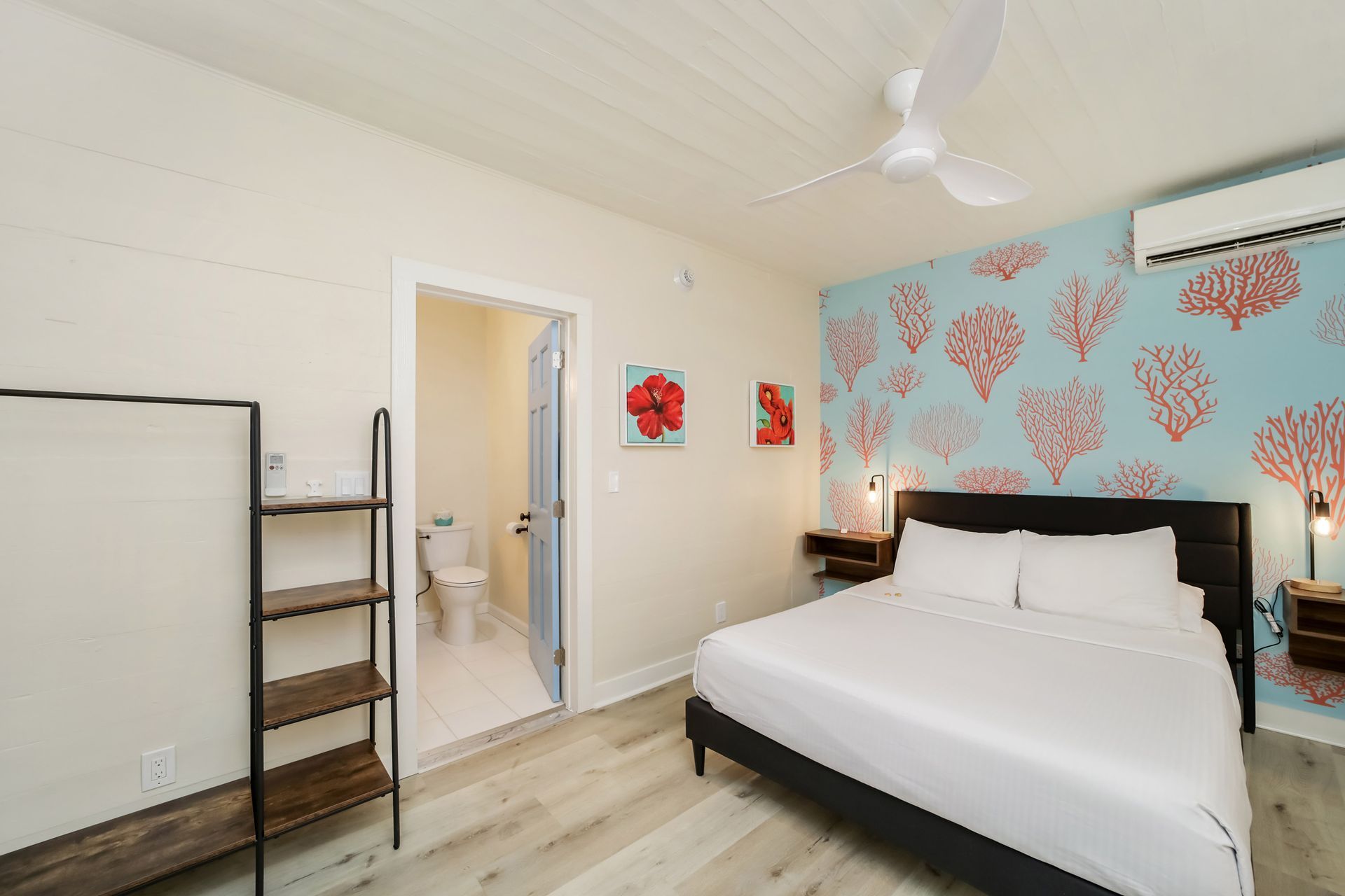 Bedroom with bed, coral wallpaper, open doorway to a bathroom, and a clothing rack.